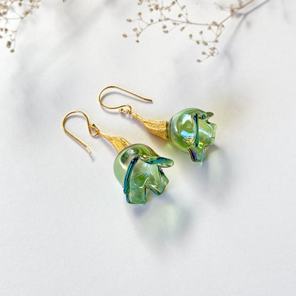Pair of green pod glass earrings with gold findings. Small branch at top of image.