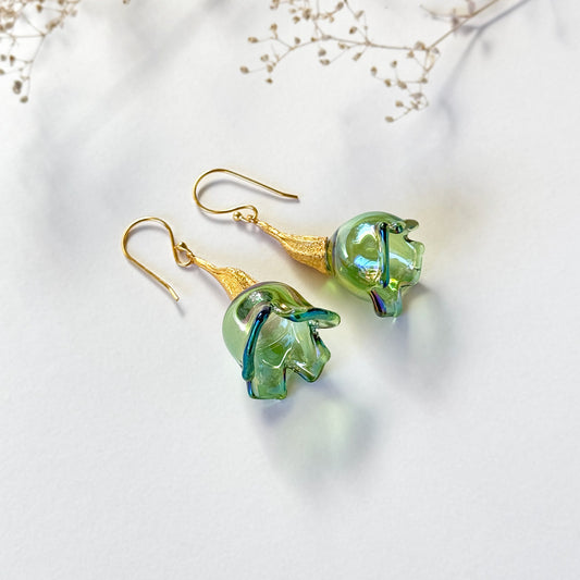 Pair of green pod glass earrings with gold findings. Small branch at top of image.