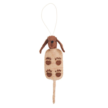 Felt ornament of a brown dog in a light brown corn dog on a stick with dark brown pawprints on it.