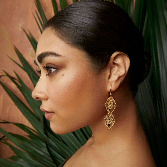 Front left view of woman wearing diamond shaped gold earrings.