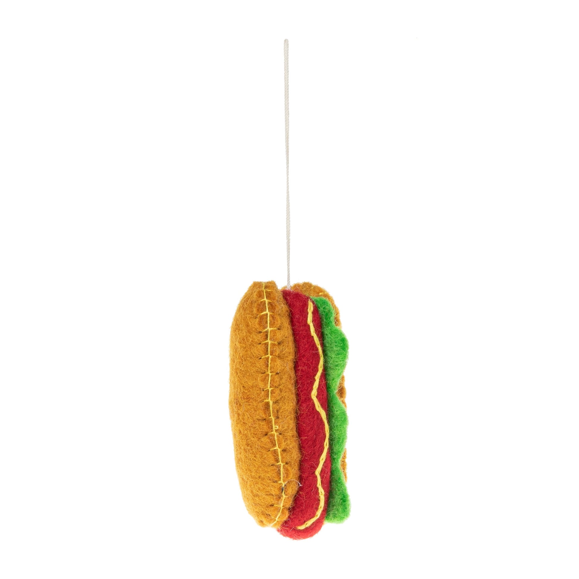 Side view of a felt ornament of a New York hot dog with mustard and relish.