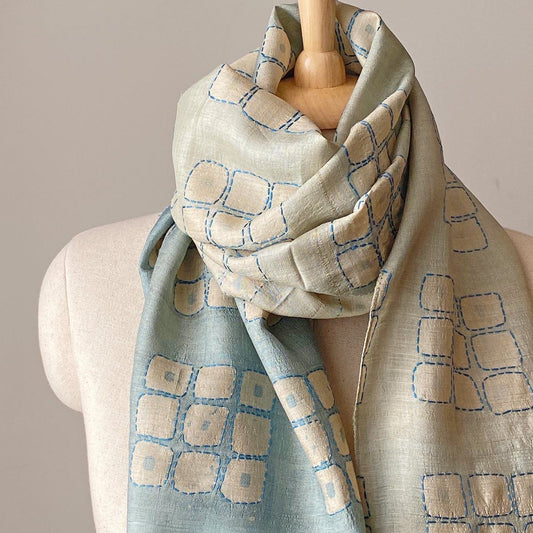 Graduated ombre silk scarf with geometric design wrapped around neck of mannikin.