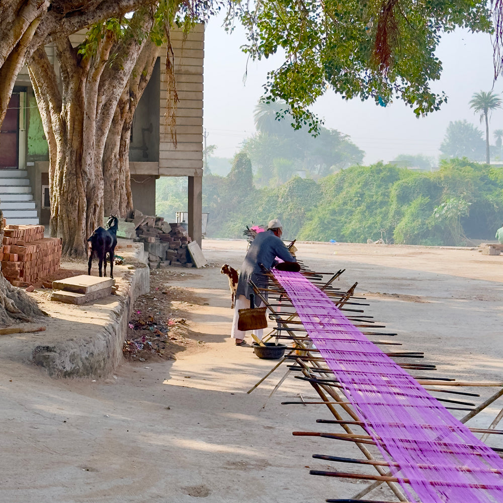 Pink Kota silk scarf in rose magenta drying on a wooden rack outdoors after hand block printing, in Kaithoon village, Rajasthan.