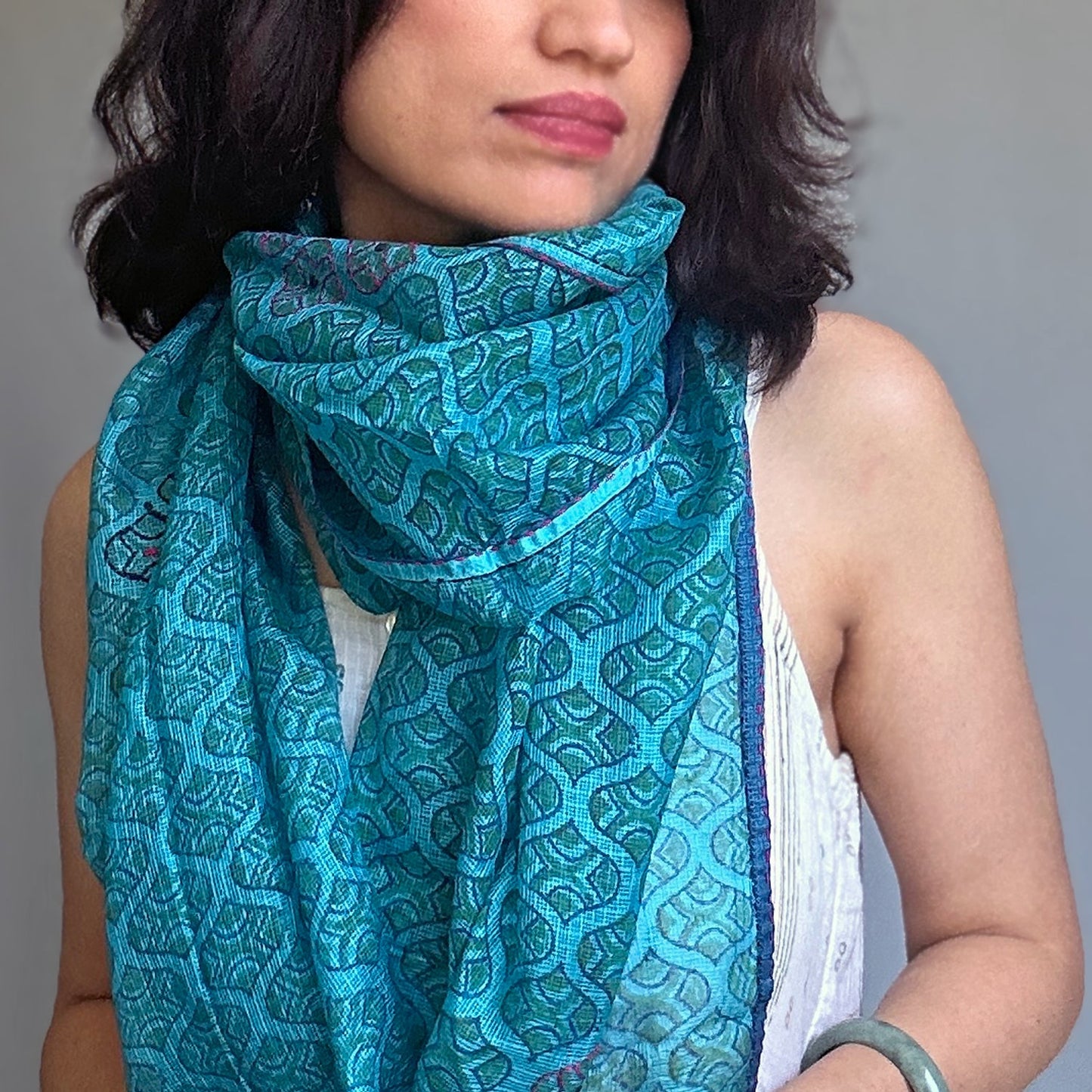 Woman wearing turquois geometric print scarf.