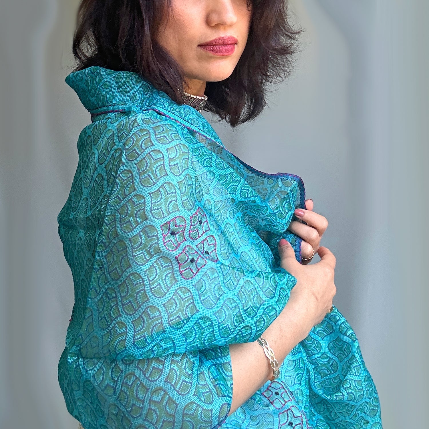 Right front view of woman wearing Turquoise shoulder wrap with geometric design.