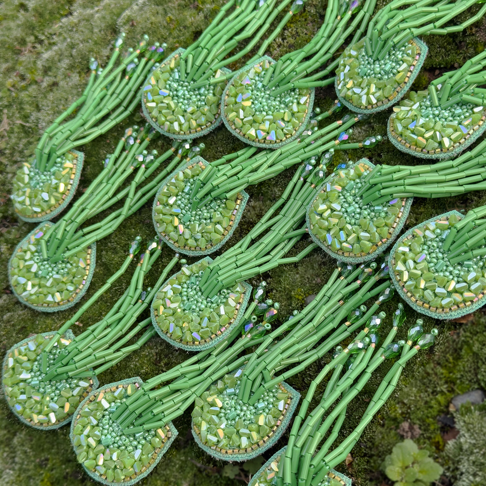 Grouping of many beaded green glass tassel earrings.