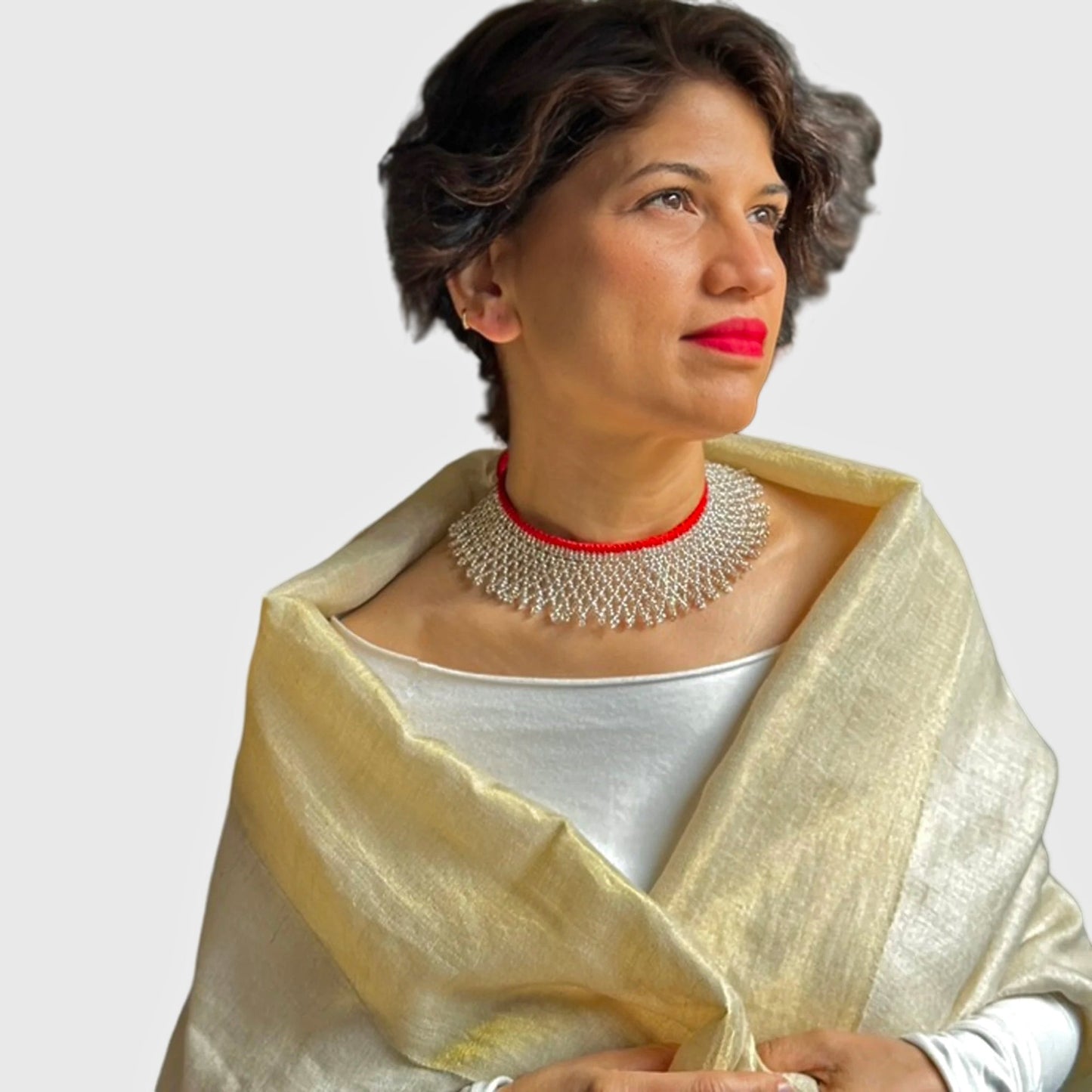 Woman with bright lipstick and matching accents on necklace, wearing gold shimmering wrap.