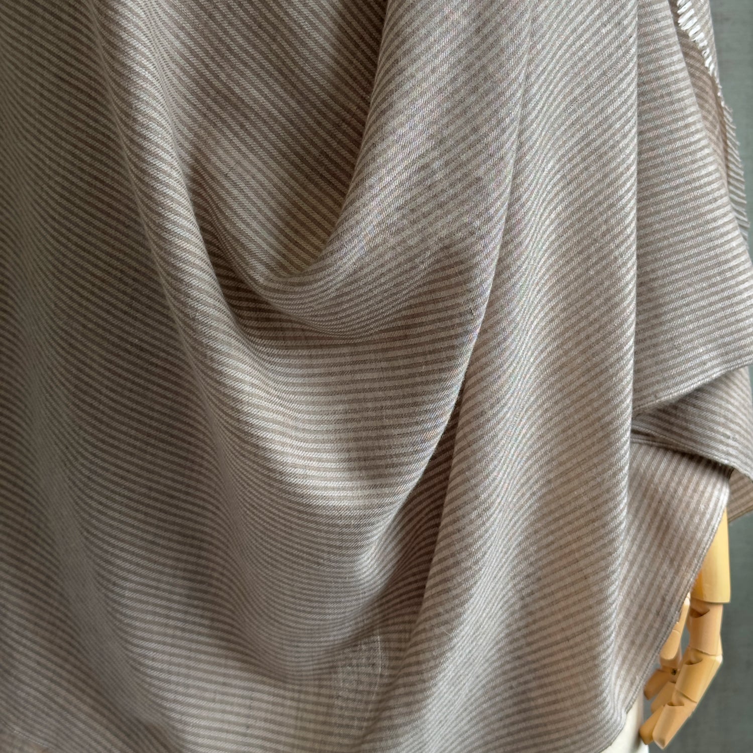 Partial view of draped taupe and brown striped scarf on manikin.