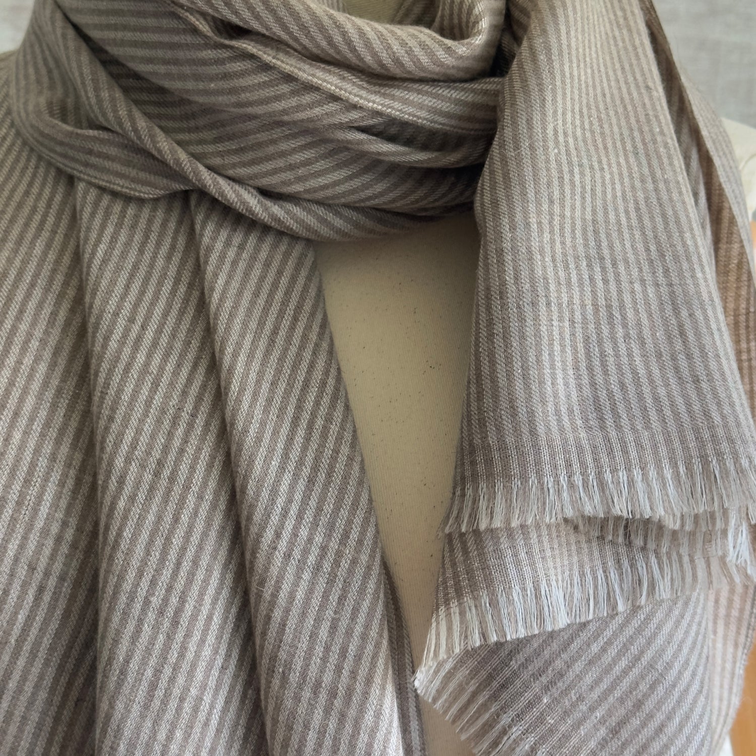 Closeup of taupe and brown striped scarf wrapped around neck.