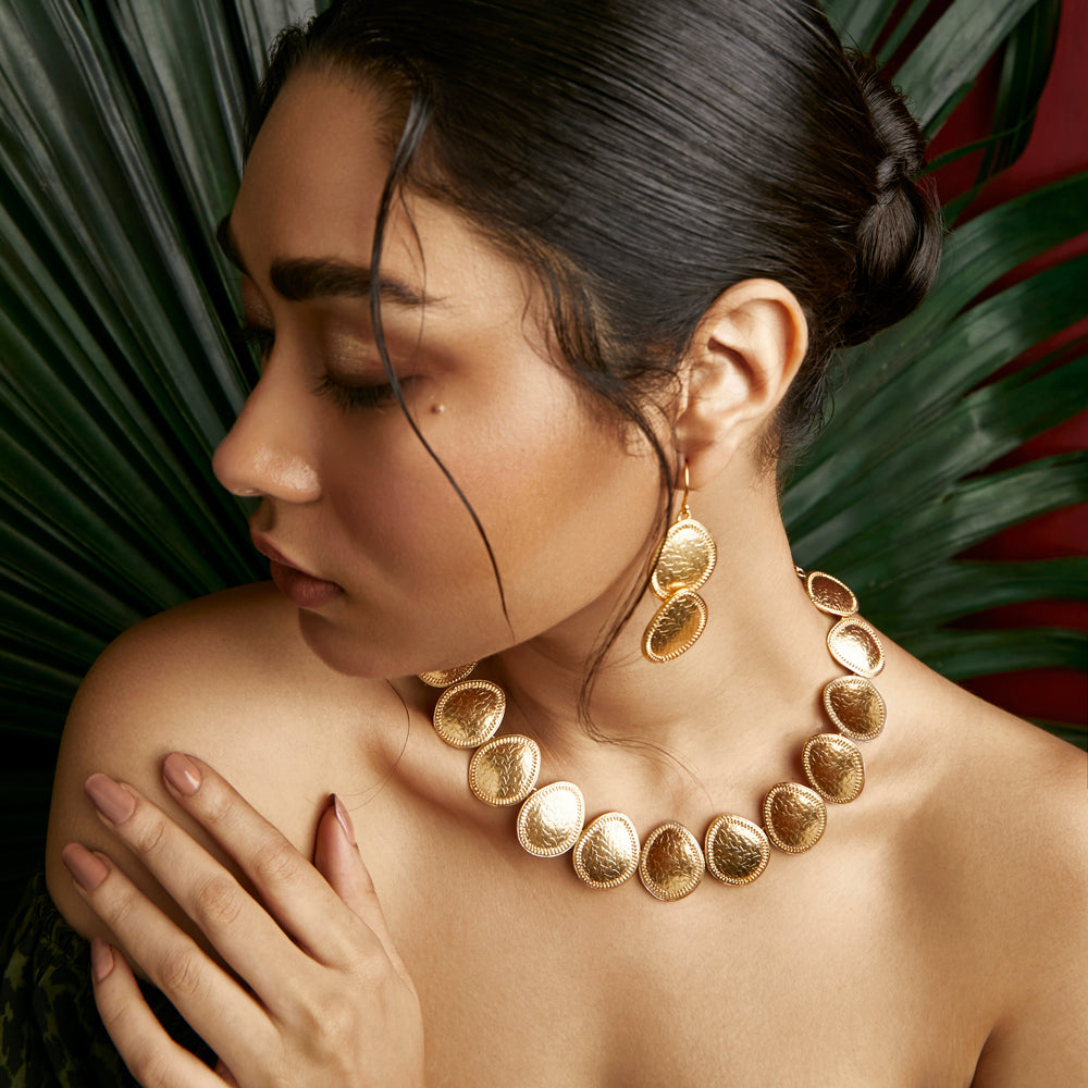 Left front view of woman wearing Pair of gold dangle earrings with etched leaf pattern.