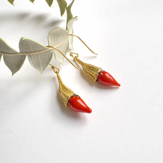 Red chili pod and gold hanging earrings on vine.