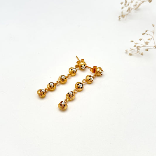 Pair of gold dangle earrings with five discs each and glass pearl in each disc.