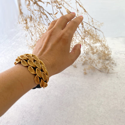 Woman's left hand wearing seedpod bracelet and touching dried flowers.