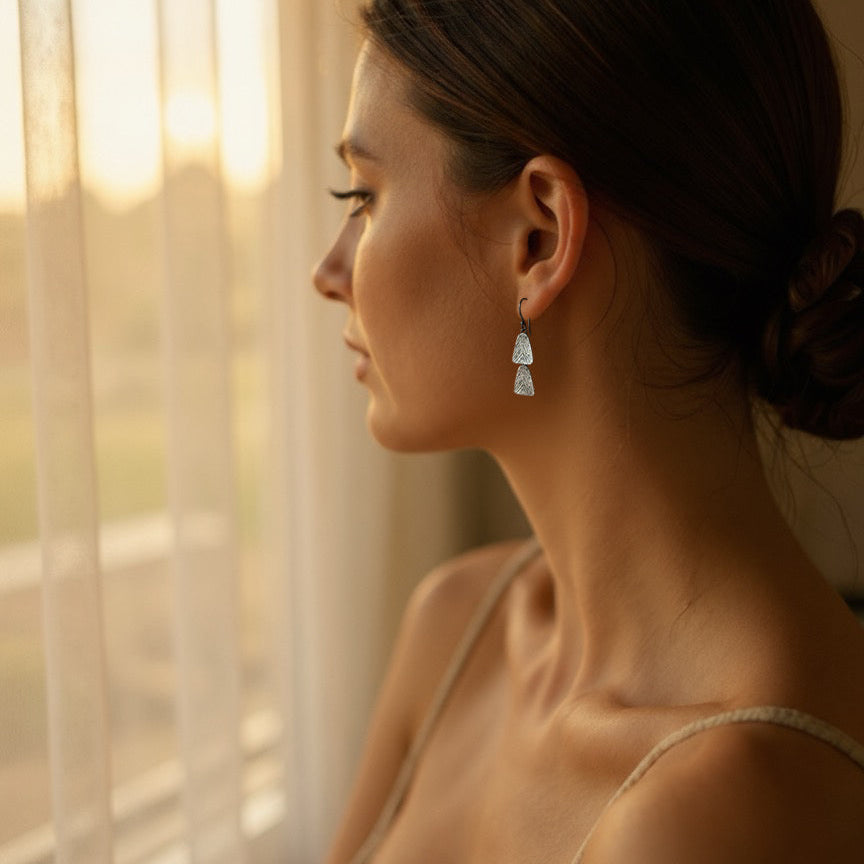 Woman with a bun and earrings looking out a window with soft light