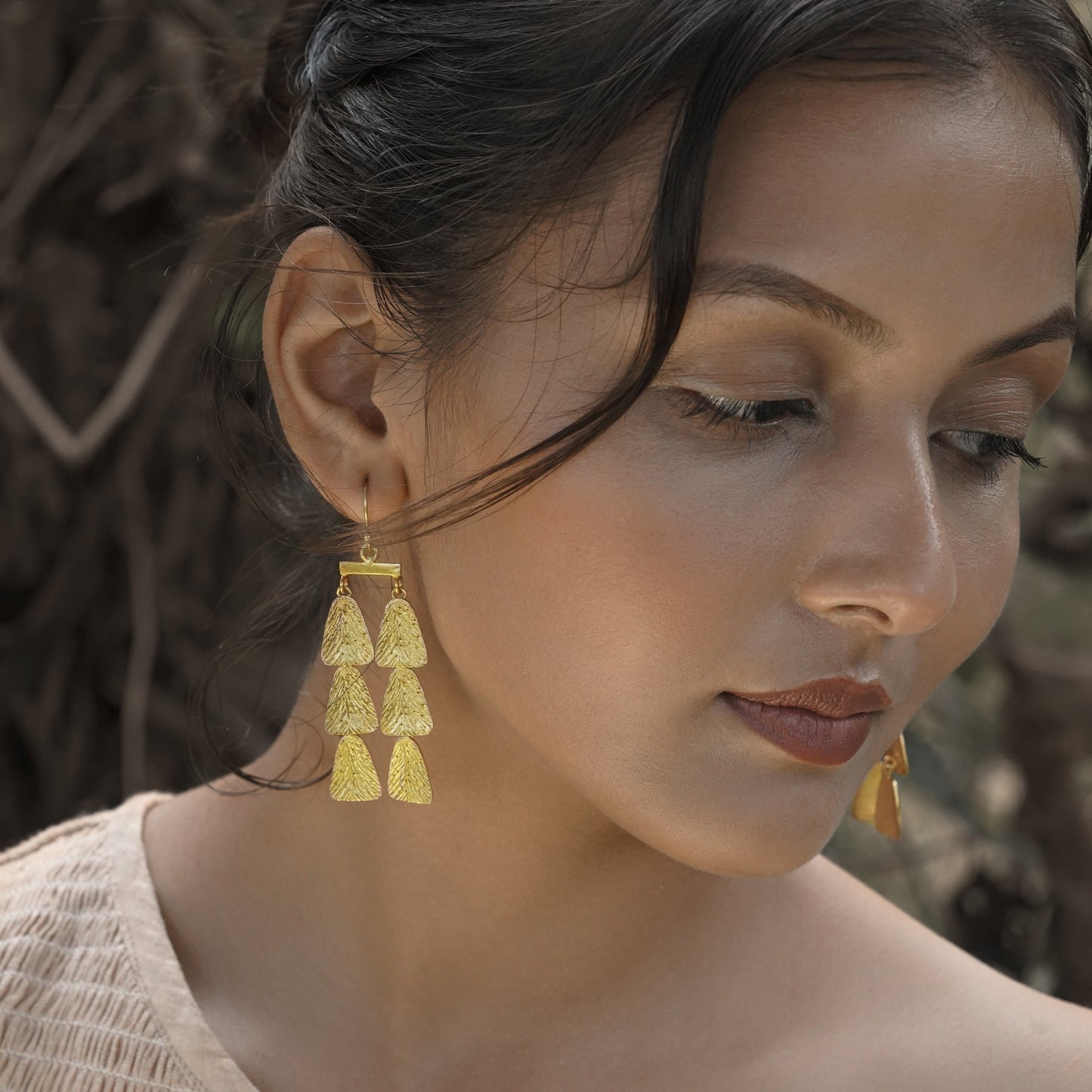 Front right view of woman wearing gold dangle earrings.