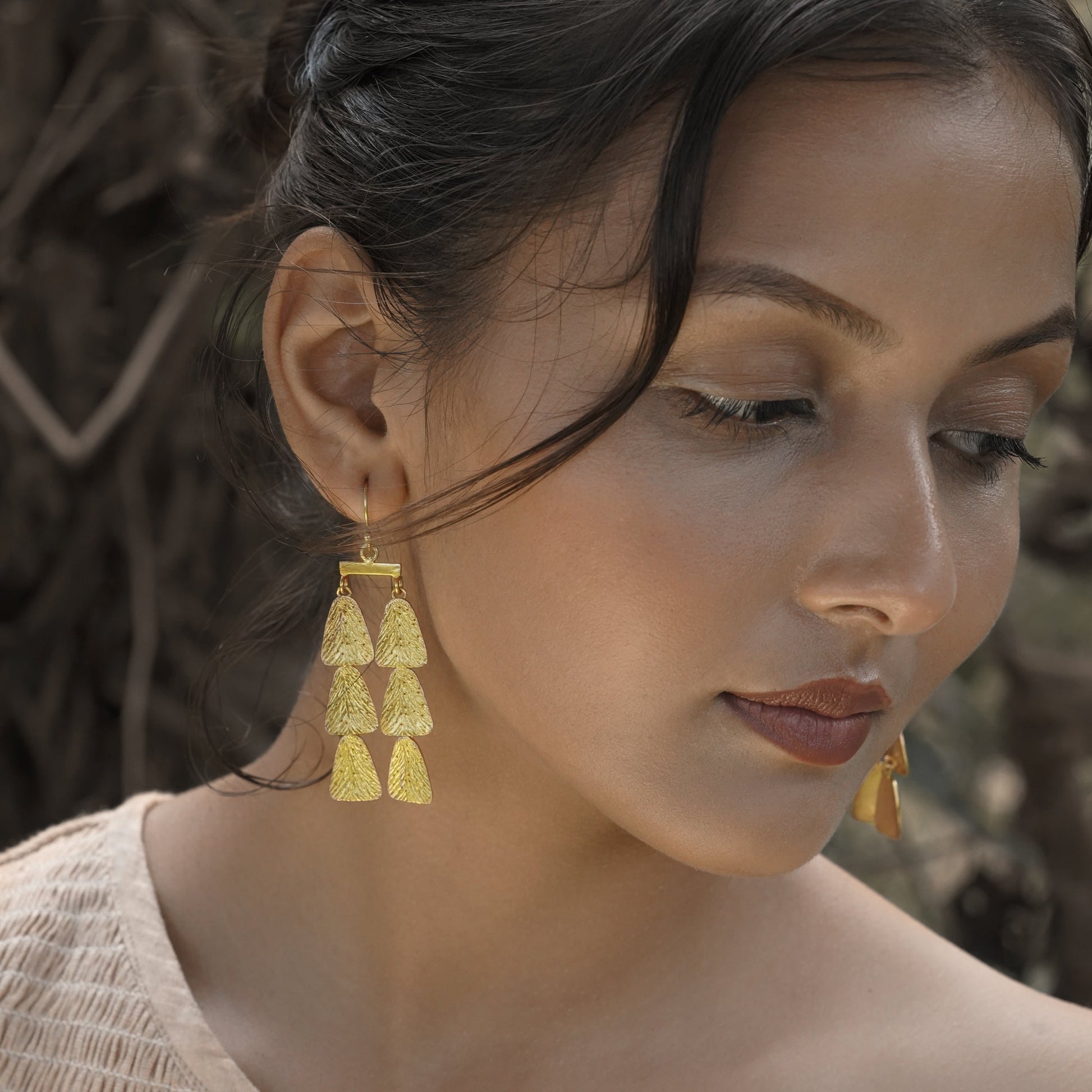 Front right view of woman wearing gold dangle earrings.