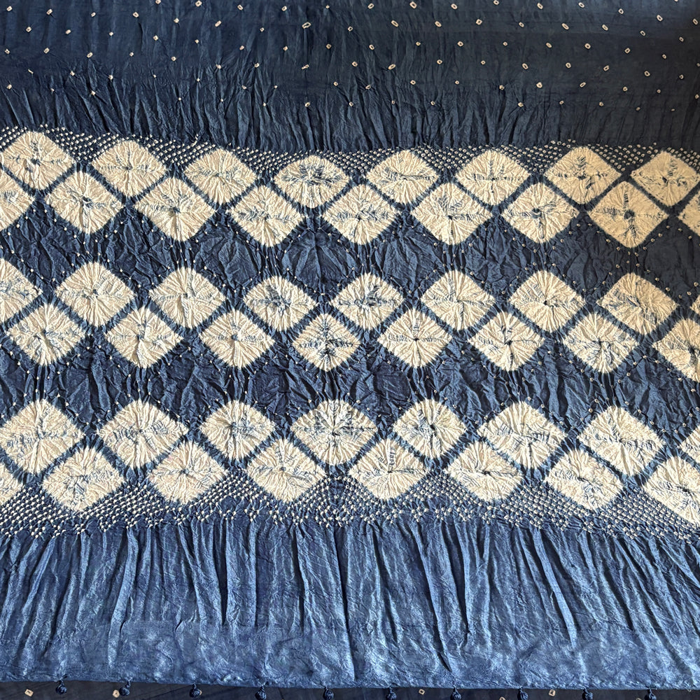 Close-up of dark blue indigo-dyed mulberry silk sari showing white diamond shibori fold-resist pattern on the pallu.