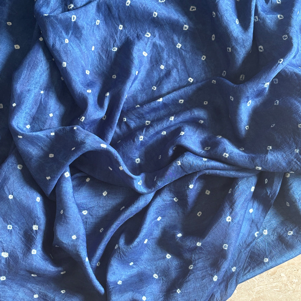 Close-up of dark blue indigo-dyed mulberry silk sari showing small white star-like bandhani dots.