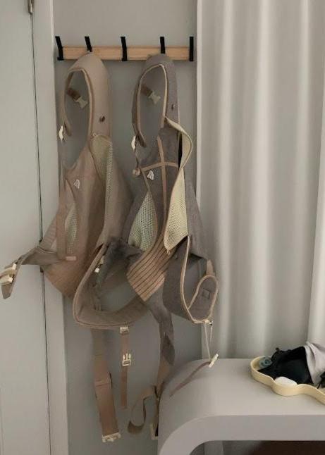 The Corset Carrier Baby Carrier in Stone on hooks by front door.