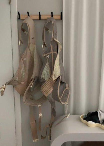 The Corset Carrier Baby Carrier in Stone on hooks by front door.