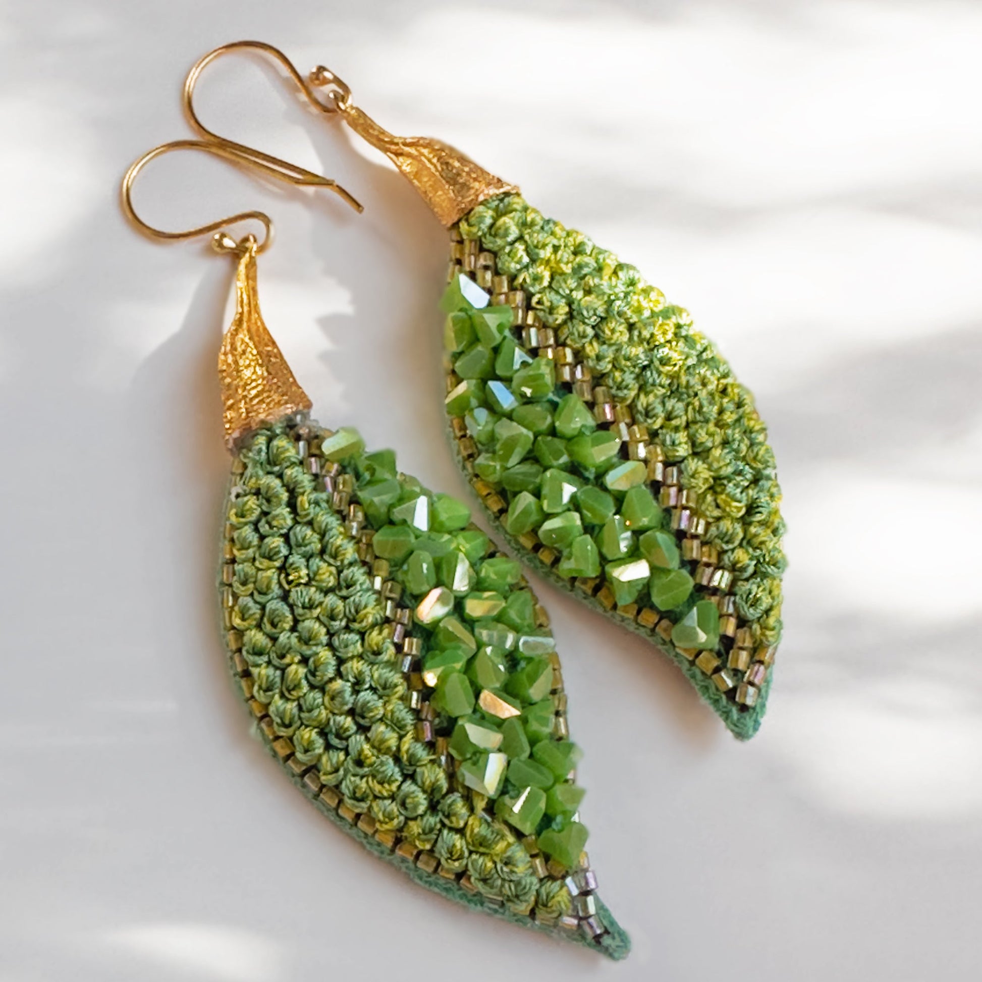 Pair of leaf shaped green glass bead earrings with gold findings.