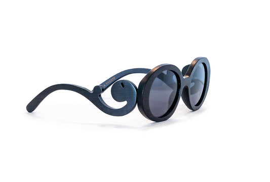 Diagonal view of black bamboo sunglasses with black frames with scroll like design on arms.