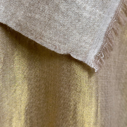 Closeup of gold material with taupe side visible at top.