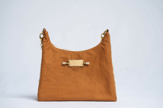 Front view of brown leather handbag with brass accents.