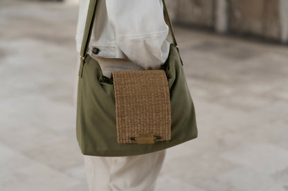 Partial side view of person wearing white, and large green bag with sisal details.